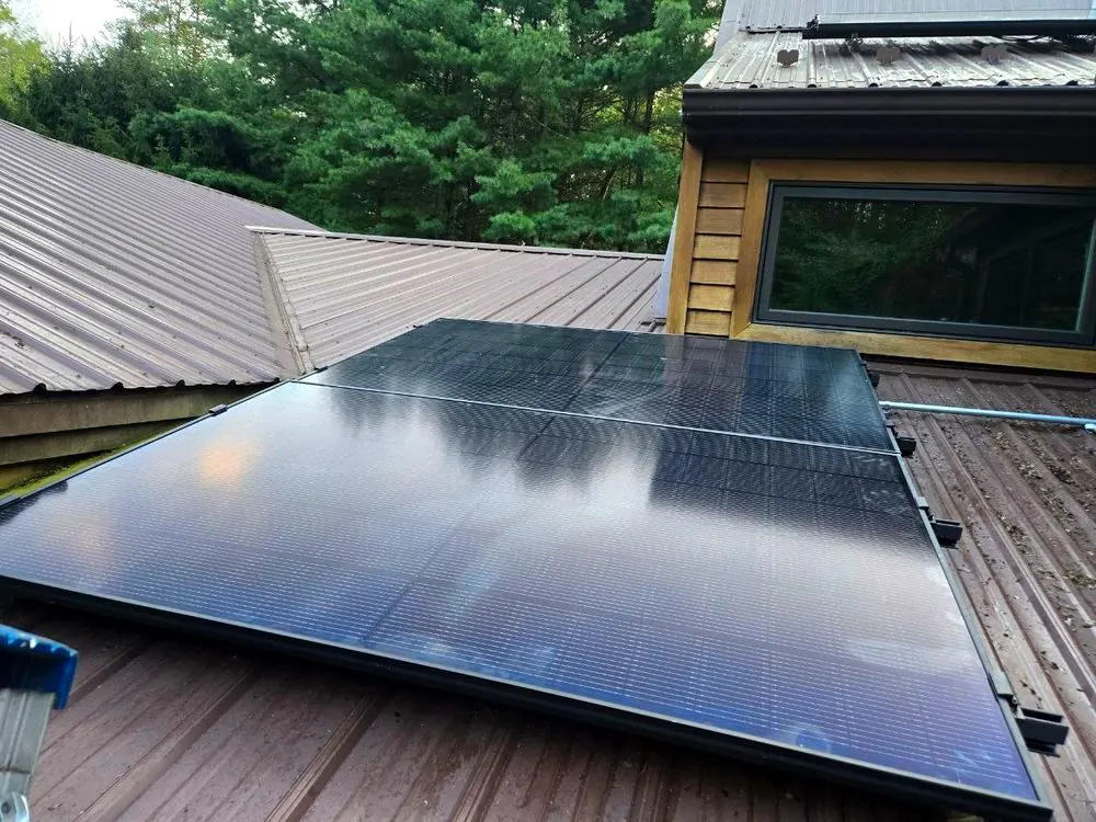 Solar modules seated on a bronze standing-seam roof next to a dormer window