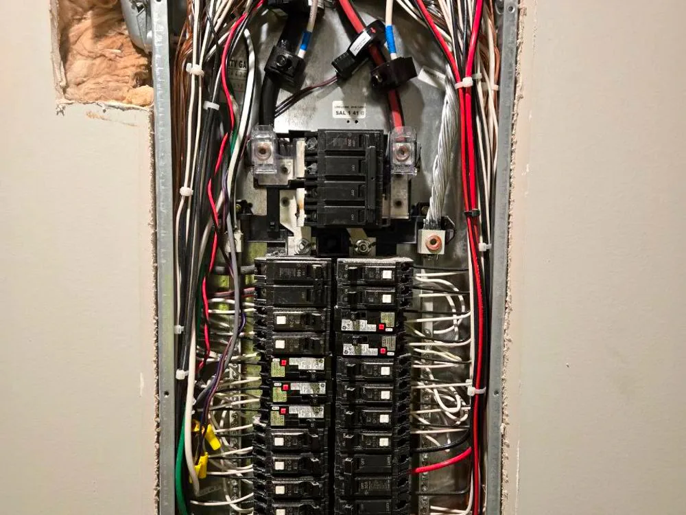 A main electrical panel opened during a service upgrade, showing breakers and branch-circuit wiring
